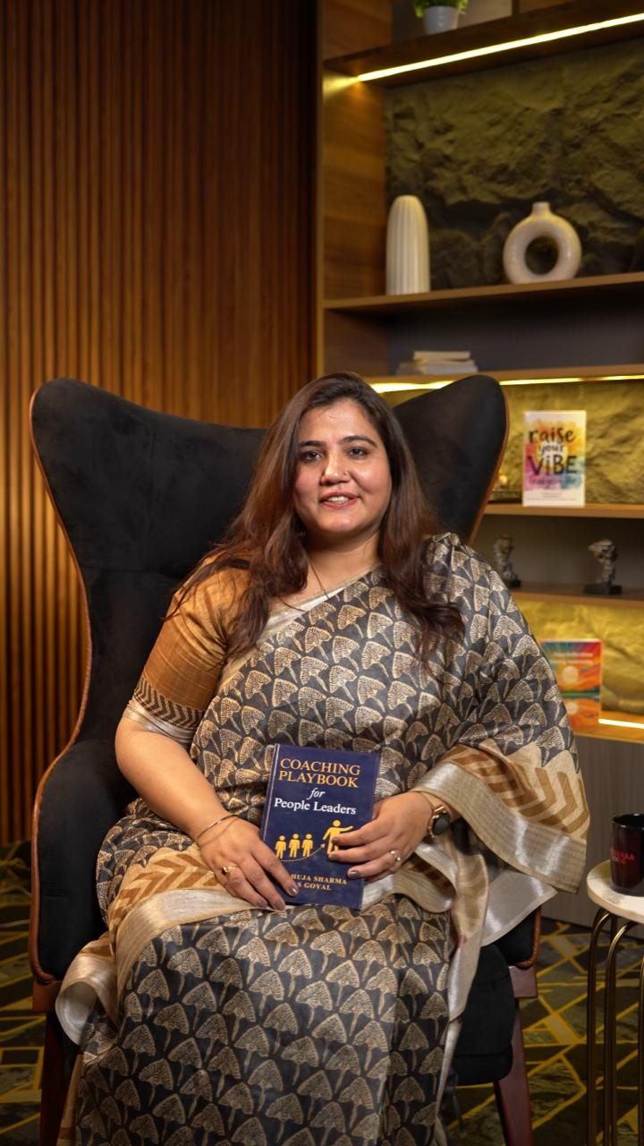 Deep Ahuja Sharma holding her book, Coaching Playbook for People Leaders